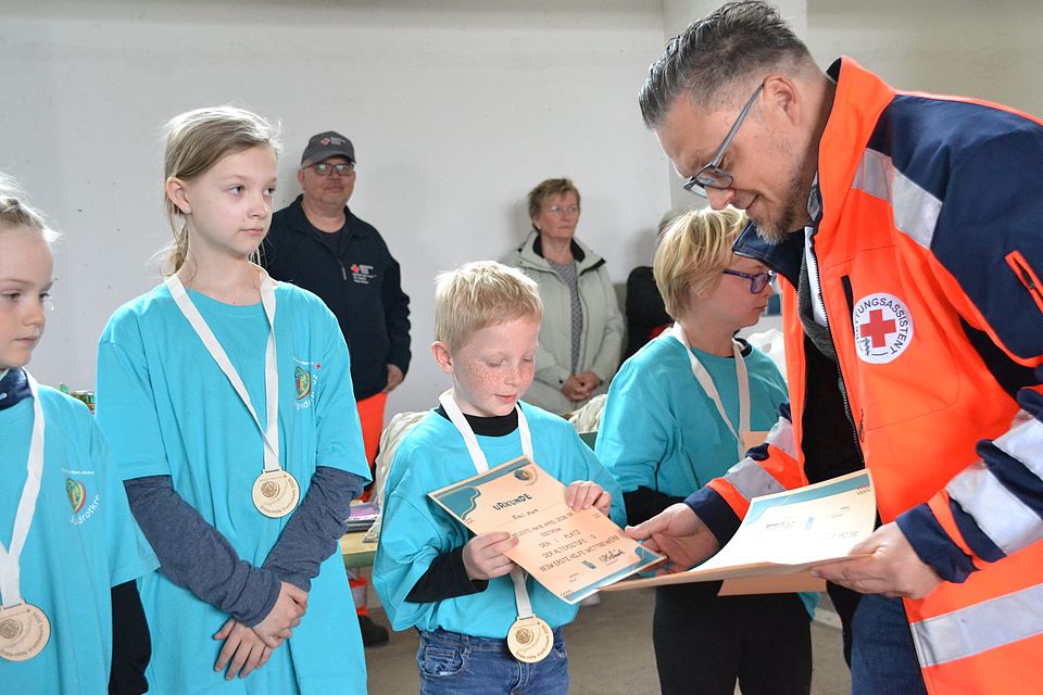 Bild zeigt Alexander Plass beim überreichen der Siegerurkunden an das JRK Team Güstrow - Altersstufe 0