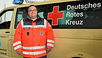 Bild zeigt den Kreisbereitschaftsleiter Marcel Stürmer vor dem Einsatzfahrzeug stehend