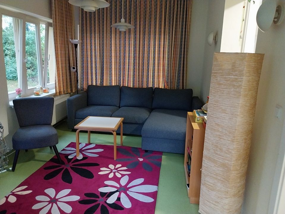 Bild zeigt einen Blick in einen Wohnraum mit Sofa, Sessel, Tisch und Sideboard