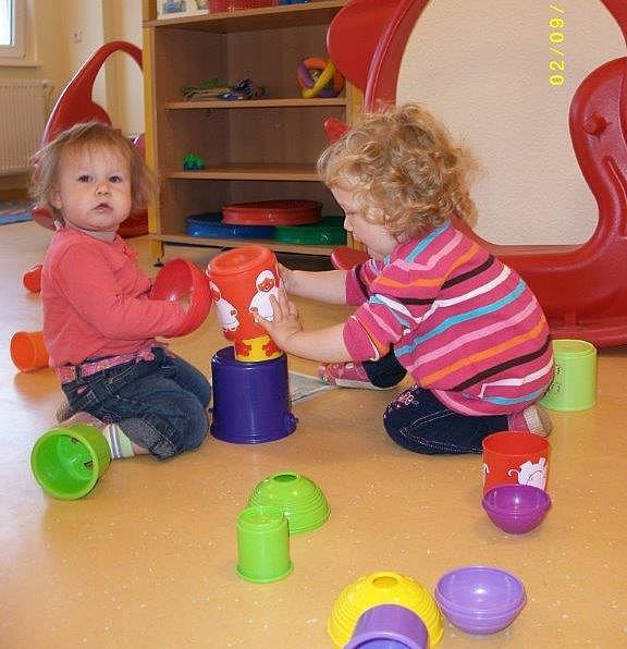 zwei kleine Mädchen bauen einen Turm mit verschieden Objekten
