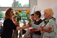 Bild zeigt Frau Cornelia Bäumer, welche die neuen Mitarbeitenden mit einer Sonnenblume begrüßt