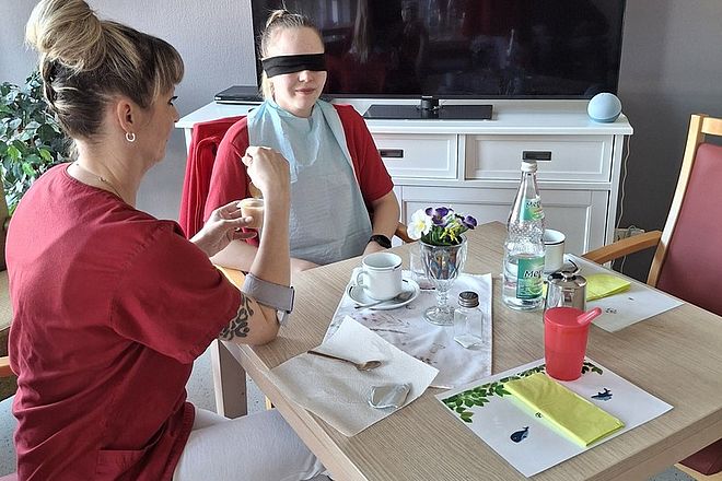 Bild zeigt die Auszubildende in der Rolle eines Heimbewohners beim Essen anreichen