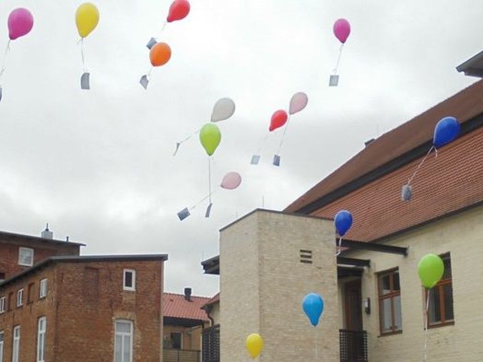 Bild zeigt aufsteigende Luftballons an denen Wunsch- und Grußkarten der Gäste der Tagespflege befestigt sind
