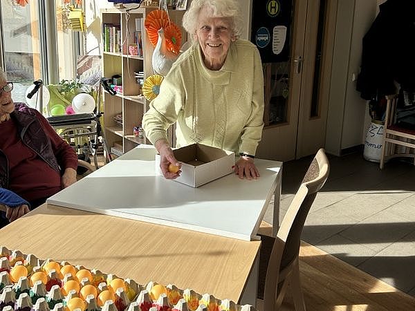 Bild zeigt eine Besucherin der Tagespflege bei einem Geschicklichkeitsspiel bei dem Tischtennisbälle in bunt bemalte Eierkartonpaletten geworfen werden müssen. Mit Aufpraller.