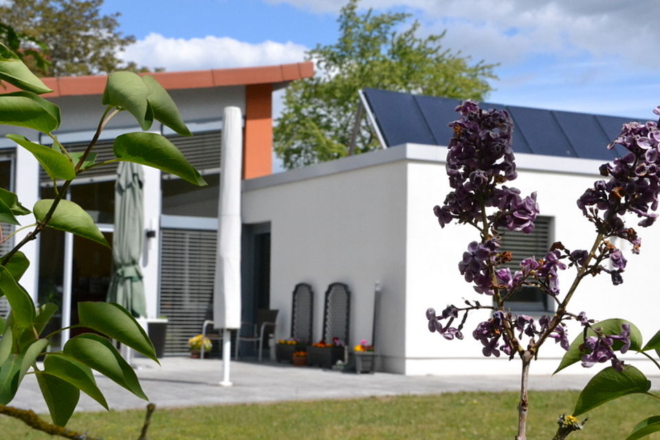 Bild zeigt eine weitere Ansicht des Gebäudes und den Terrassenplatz mit Sonnenschirm