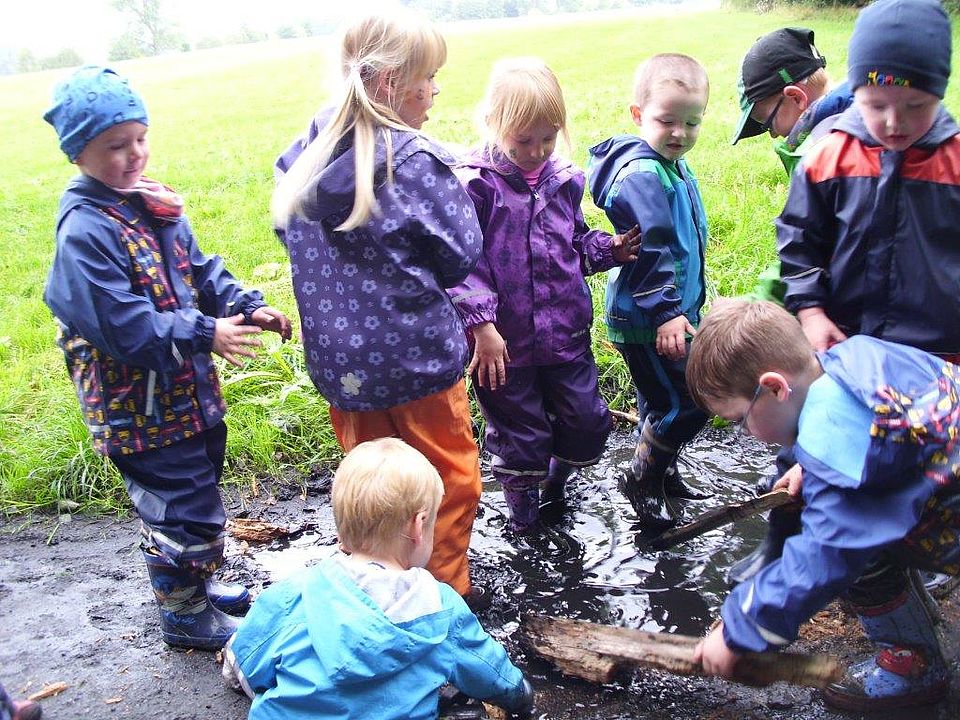 Gruppe von Kindern stampfen in einer Pfütze