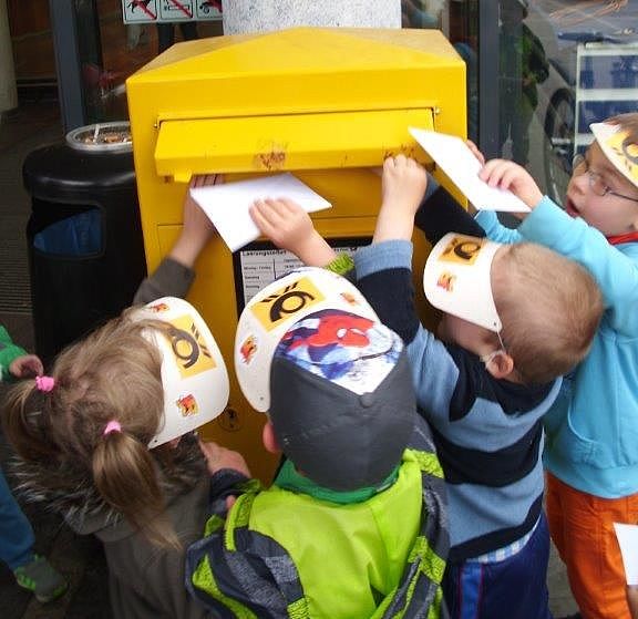 Kinder stecken Briefe und Karten in einen Briefkasten