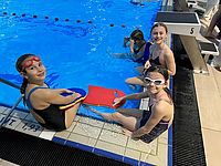 Bild zeigt Kinder am Rand eines Schwimmbeckens sitzend