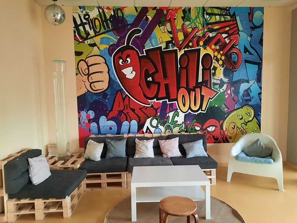 Bild zeigt den "Chill-Raum" mit Sitzecke aus Europaletten und Sitzkissen sowie ein Graffitibild  an der Wand