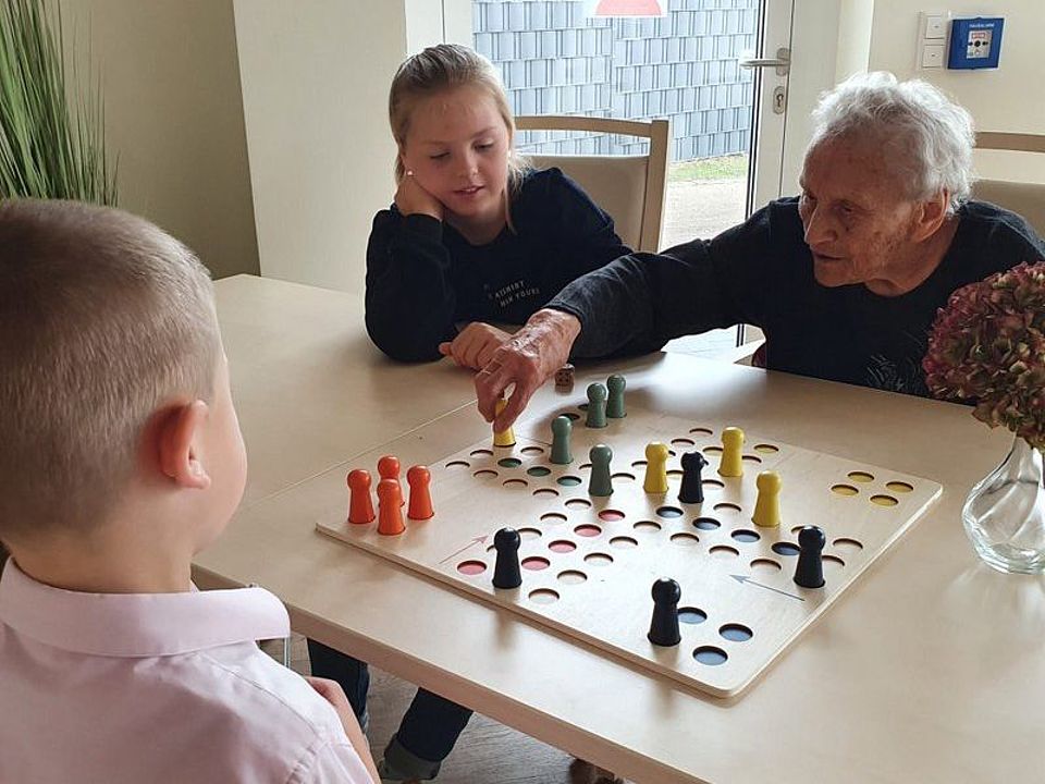 Bild zeigt einen Besucher der Tagespflege, welcher mit Besucherkindern Mensch ärgere dich nicht spielt.