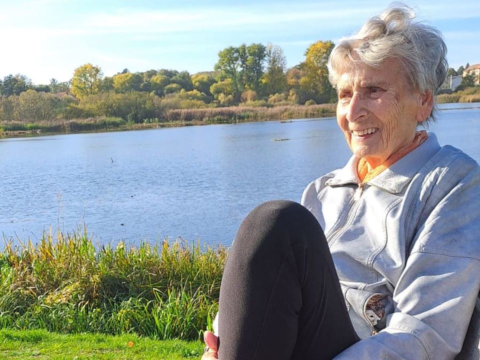 Bild zeigt eine Besucherin der Tagespflege am See auf einer Bank sitzend und entspannen