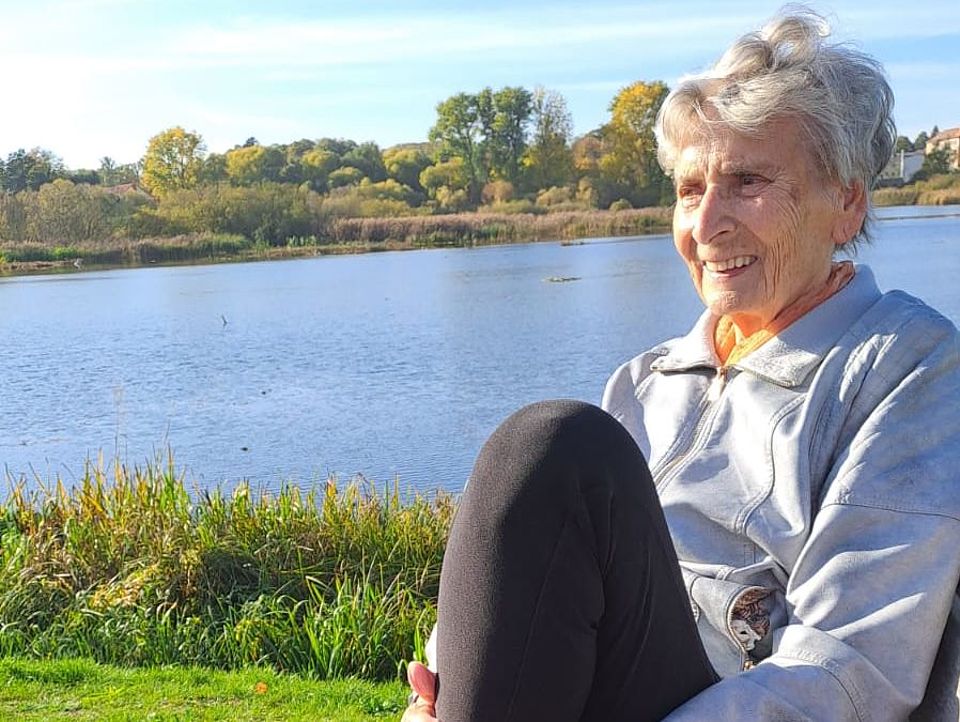 Bild zeigt eine Besucherin der Tagespflege am See auf einer Bank sitzend und entspannen