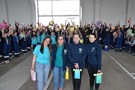 Bild zeigt die vier Hauptorganisatoren des Wettbewerbs. Im Hintergrund stehen alle Mannschaften im Karree und jubeln