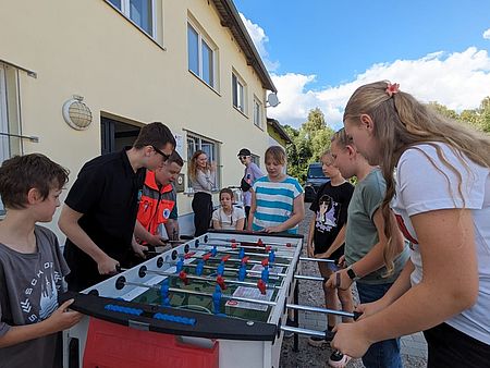 Bild zeigt Teilnehmer des Camps bei einem Tischkickerspiel vor dem Ehrenamtszentrum im Güstrower Heideweg
