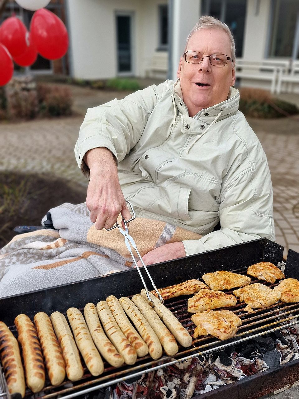 Bild zeigt Bewohnenden mit der Grillzange am Grill