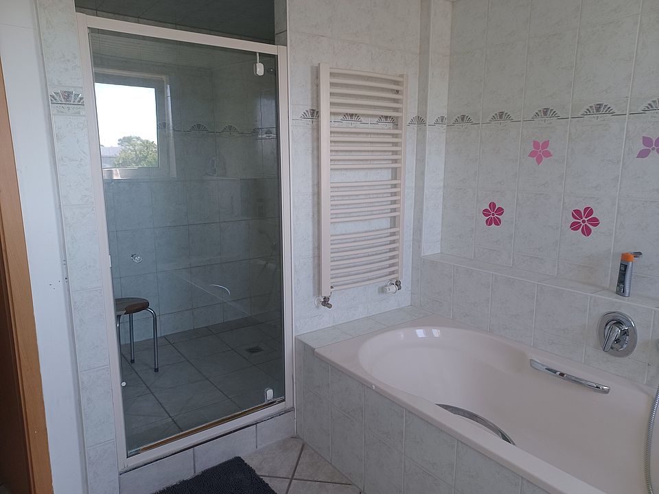 Bild zeigt den Blick in das große Badezimmer mit Wanne und Dusche