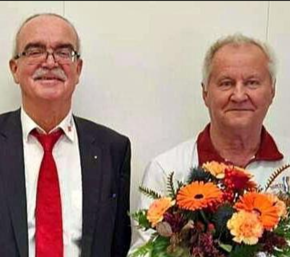 Bild zeigt Herrn Werner Kuhn und Rudi Heitmann nebeneinander stehend. Herr Heitmann hält einen sehr großen Blumenstrauß mit Gerbera, Nelken und Rosen in der Hand