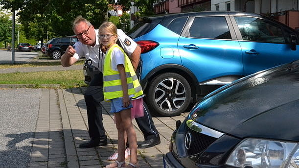 Bild zeigt die kleine Leni mit Karsten Hamann (Polizist) wie die Straße überquert wird