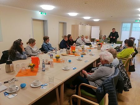 Bild zeigt die Teilnehmer der Veranstaltung an der langen Tischtafel sitzend