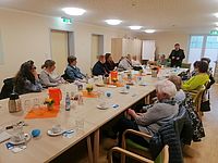 Bild zeigt die Teilnehmer der Veranstaltung an der langen Tischtafel sitzend