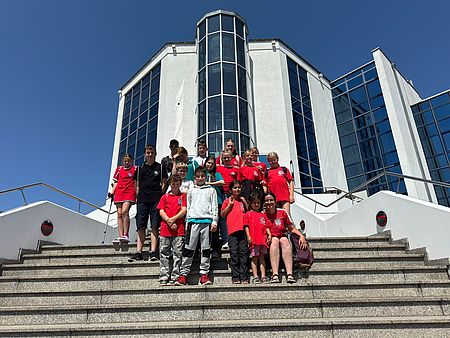 Bild zeigt die gesamte Teilnehmergruppe in einem Gruppenbild auf den Stufen vor dem Gebäude des HCC