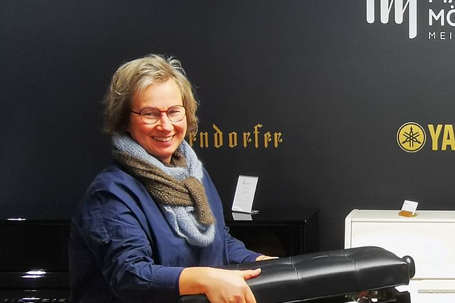 Bild zeigt Frau Petra Möller vom Pianohaus Möller mit dem Klavierhocker in der Hand