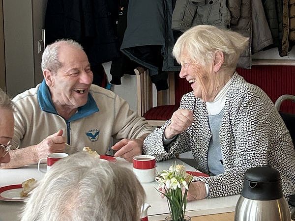 Bild zeigt mehrere Tagesgäste lachend an der Kaffeetafel