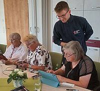 Bild zeigt Moritz Bauriedl der Seniorinnen Handy und Tablet in der Nutzung erklärt