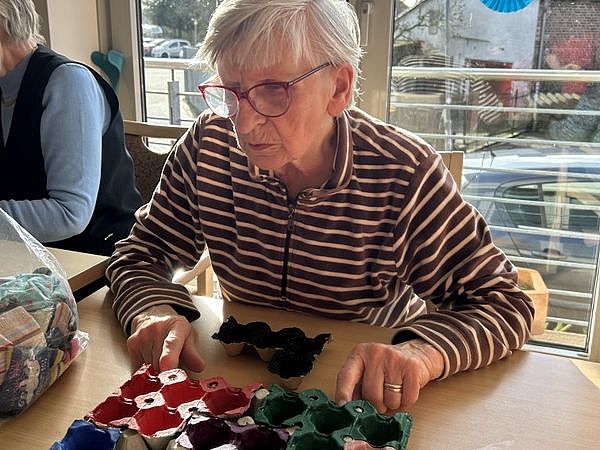 Bild zeigt eine Besucherin der Tagespflege mit einem von den Mitarbeitenden und den Gästen selbst erstellten Gedächtnisspiel aus Eierkartonpaletten - eine Art Tetrisspiel