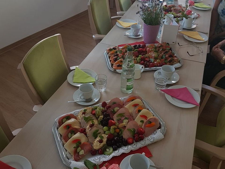 Bild zeigt einen gedeckten Frühstückstisch mit Platten von belegten Brötchen und Schnittchen