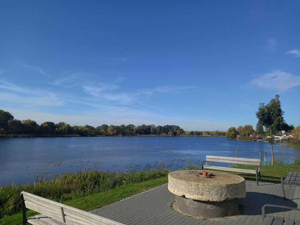 Bild zeigt eine Sitz- und Ruhemöglichkeit am See mit Blick auf das Wasser.