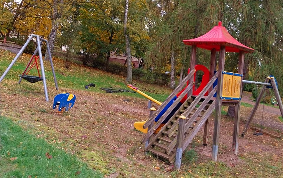 Bild zeigt den Spielplatz mit Schaukel, Kletterturm und Wippe