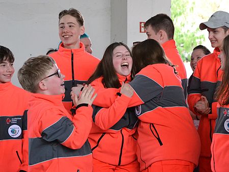 Bild zeigt die Mitglieder des JRK Güstrow nach bekanntgabe des Ergebnisses in der Alterstufe 2. Alle jubeln und liegen sich in den Armen. Fröhliche Gesichter.