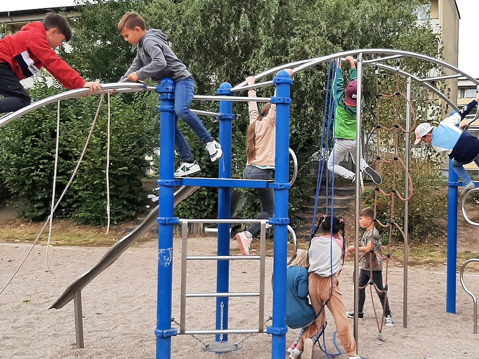 Bild zeigt mehrere Kinder auf einem großen Klettergerüst sie spielen fangen auf dem Klettergerüst