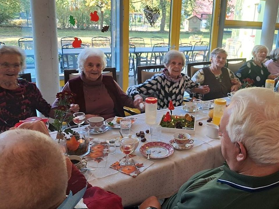 Bild zeigt viele Besucher der Tagespflege an einem schön gedeckten Tisch in einer lustig, fröhlichen Feierrunde.