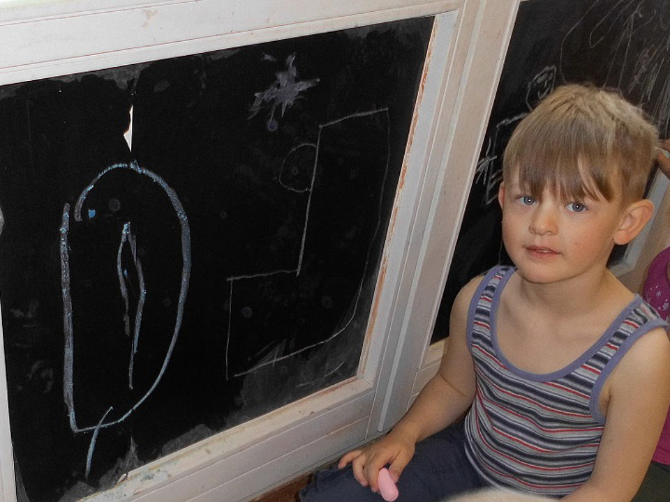 Bild zeigt einen Jungen an einer Maltafel