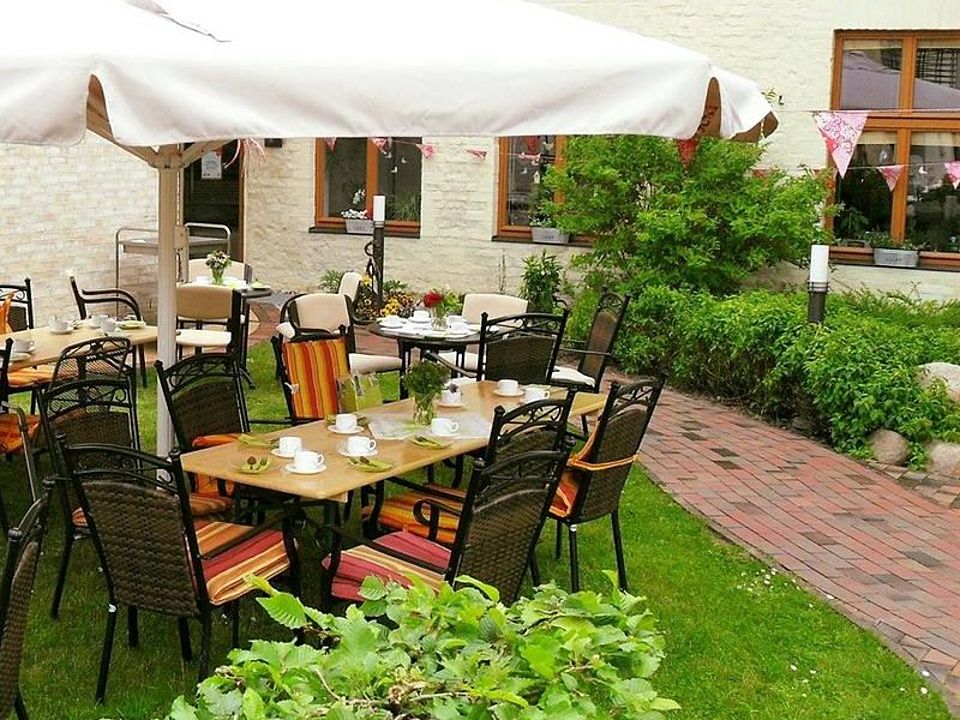 Bild zeigt eine, im Innenhof auf dem Rasen gedeckte Kaffeetafel mit Sonnenschirm