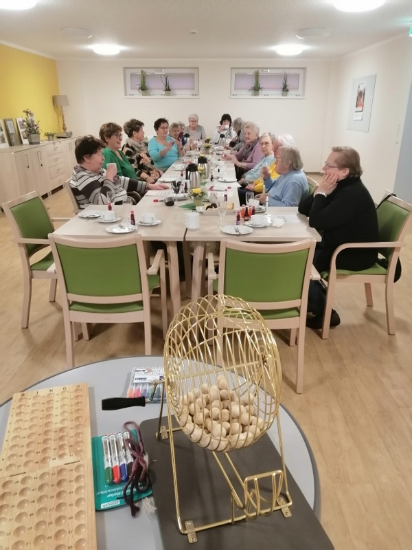 Bild zeigt die lange Kaffeetafel mit den Teilnehmern und im Vordergrund die Bingo-Trommel