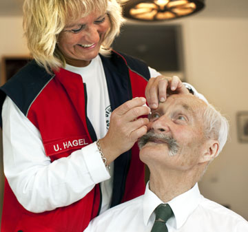 Bild zeigt eine Pflegefachkraft, die einem Patienten Augentropfen verabreicht 