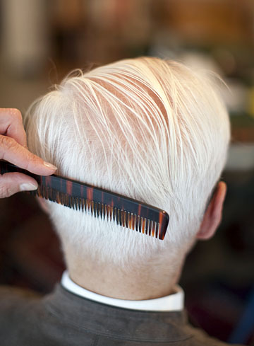 Bild zeigt den Hinterkopf eines Seniors, dem die Haare gekämmt bzw. geschnitten werden