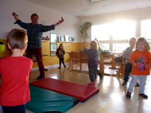 Gruppe von Kindern tanzt und singt mit dem Erzieher