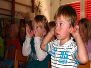 Gruppe von Kindern beim anschauen eines Puppentheaters mit ganz großen Augen und roten Ohren