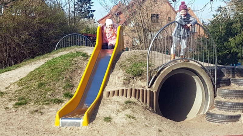Rutsche und Tunnel zwei Kinder stehen auf einem Hügel an einer Rutsche