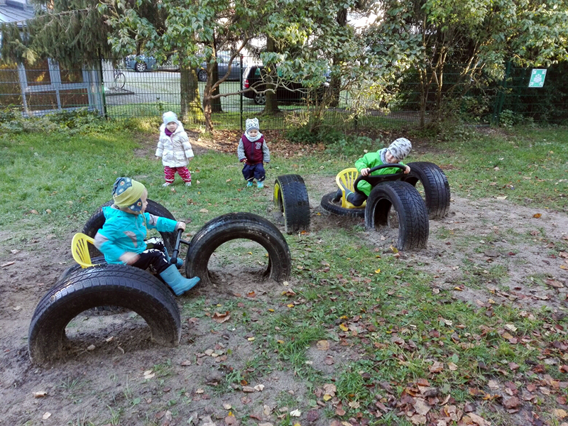 Bild zeigt Kinder auf einem Spielplatz mit eingegrabenen Autoreifen