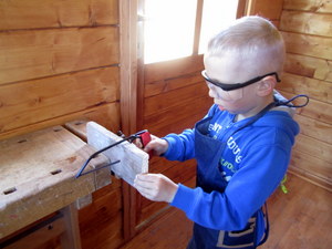 in der Werkstatt arbeit ein Junge an einem Holzstück