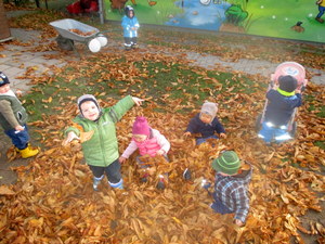 Gruppe von Kindern spielt im Freien mit Herbstlaub