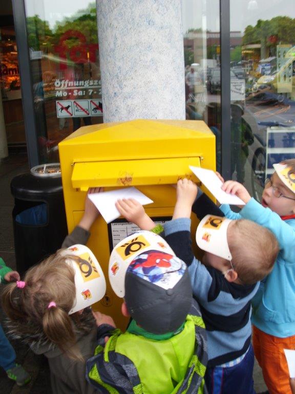 Kinder stecken Briefe und Karten in einen Briefkasten