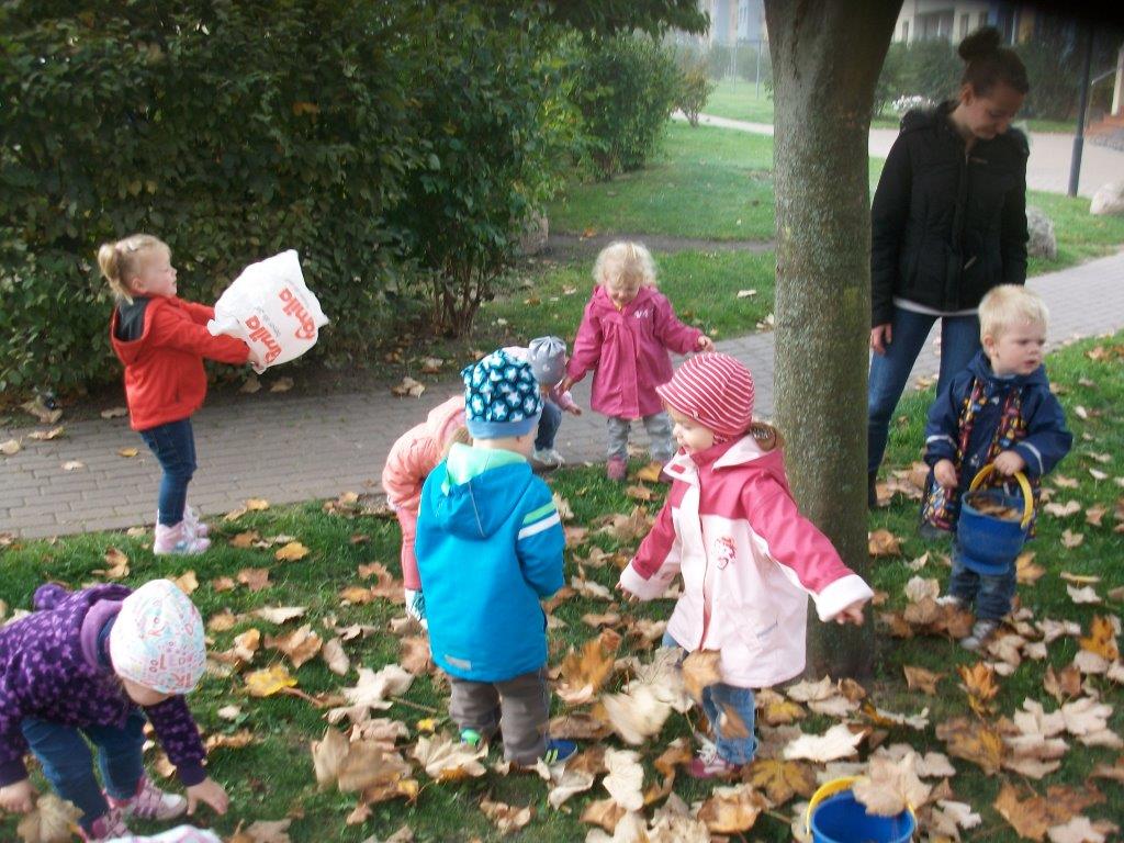 Kinder sammeln Herbstlaub im Park