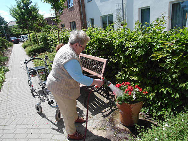 Bewohnerin pflegt Blumen in der Außenanlage