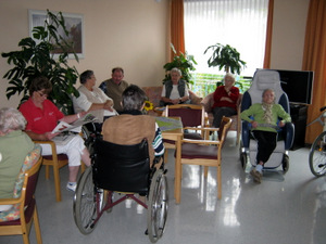 Gruppe von Bewohnern sitzen in der Runde und lesen gemeinsam Zeitung 